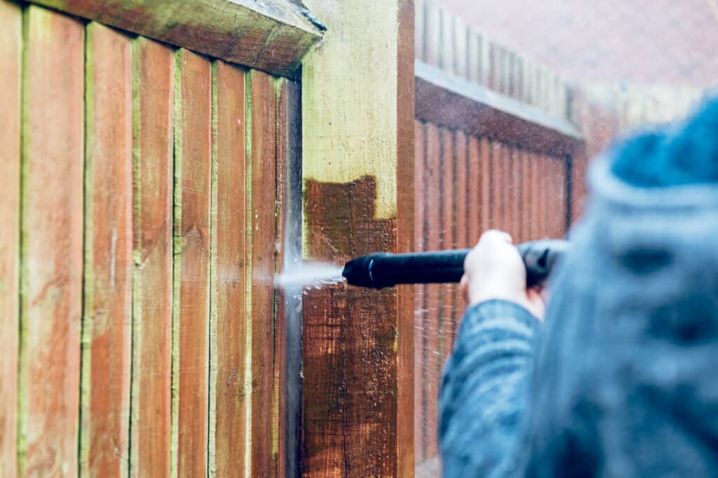 Soft wash Pressure Cleaning and Renovating Wood Fence with powerful jet wash or pressure washer, spring cleaning of the garden and house
